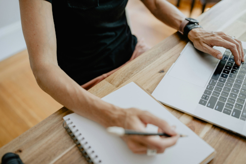 Poste de travail avec prise de notes et consultation d’un ordinateur illustrant la préparation des publications financières d’HERIGE Industries