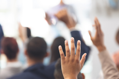Mains levées lors d’une séance de vote illustrant la participation aux Assemblées Générales d’HERIGE Industries
