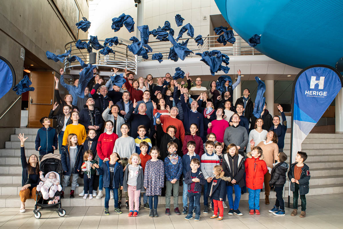Groupe intergénérationnel réuni dans un espace intérieur illustrant la transmission et l’histoire au sein d’HERIGE Industries